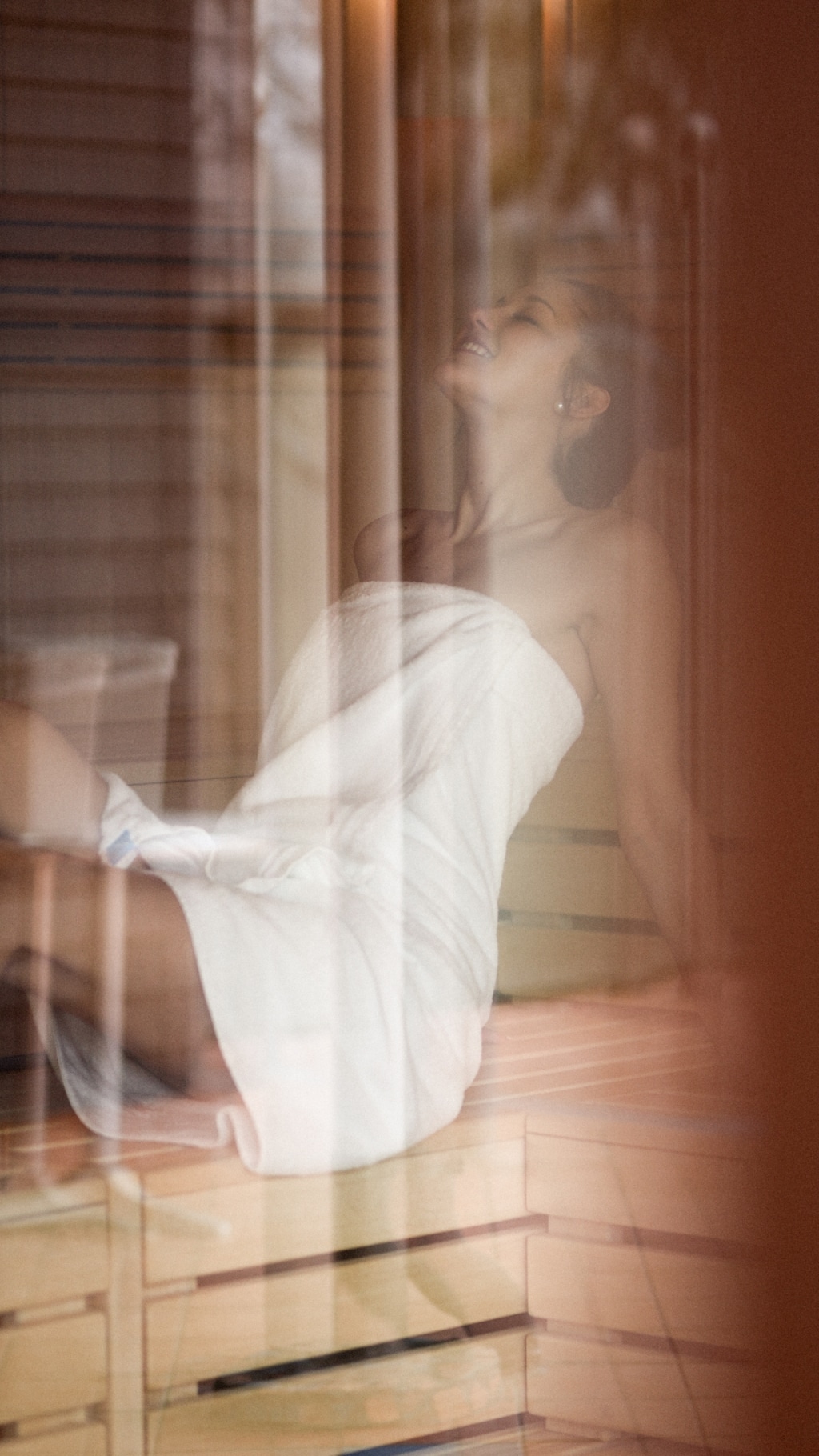Eine junge Frau sitzt in der Sauna und genießt ihren Aufenthalt sichtlich.