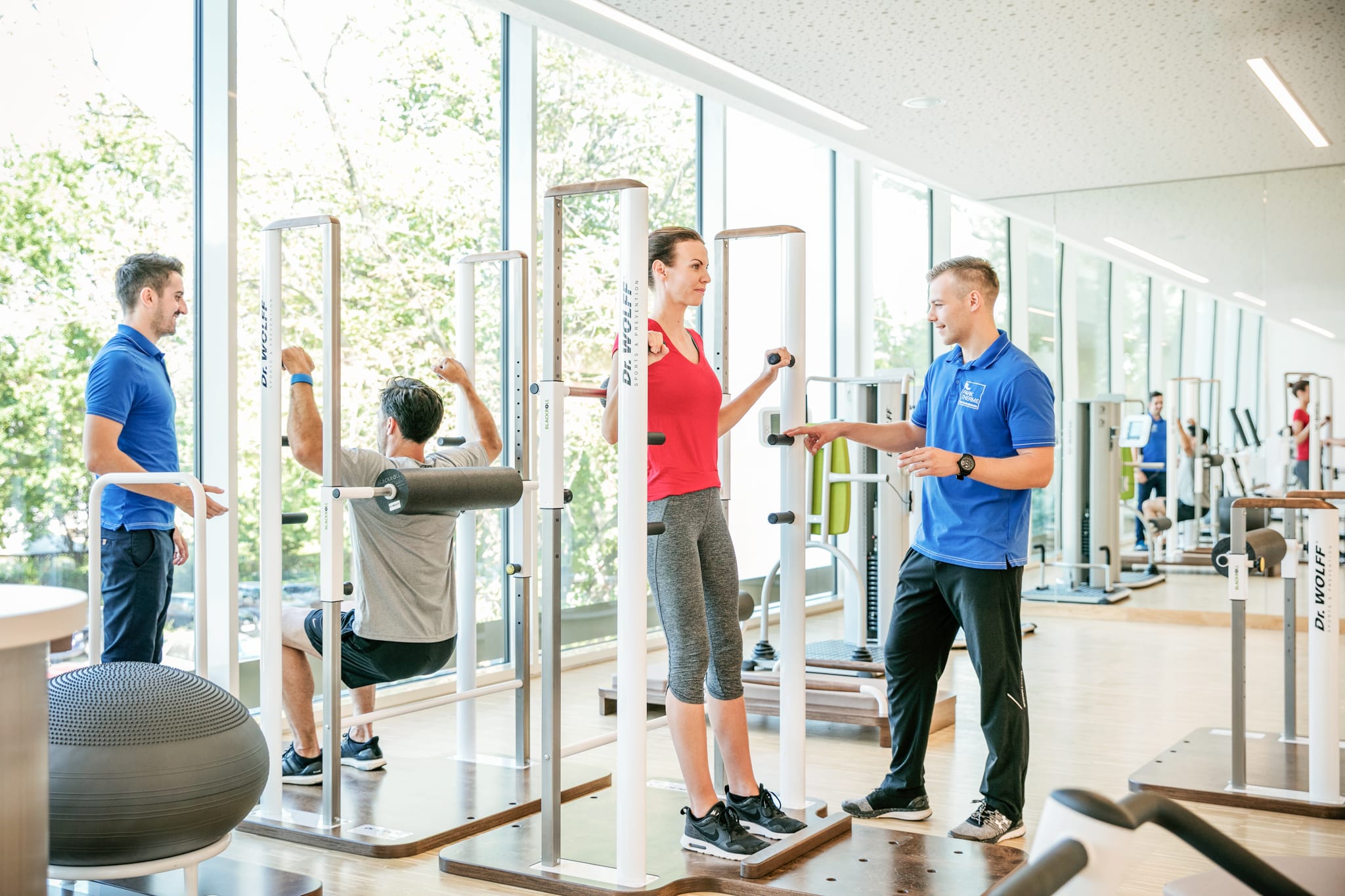 Zwei Physiotherapeuten erklären einem trainierenden Pärchen die Trainingsgeräte im Medizinischen Trainingszentrum.