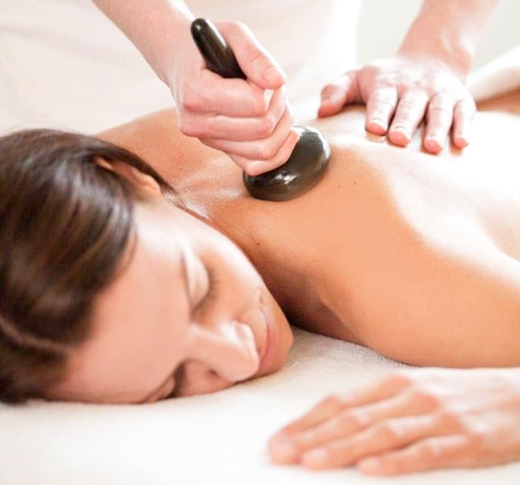 Eine Dame liegt auf einem Behandlungstisch und genießt eine wohltuende Massage.