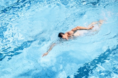 Ein Mann schwimmt im 50-Meter-Sportbecken und führt dabei eine Kraulbewegung durch.
